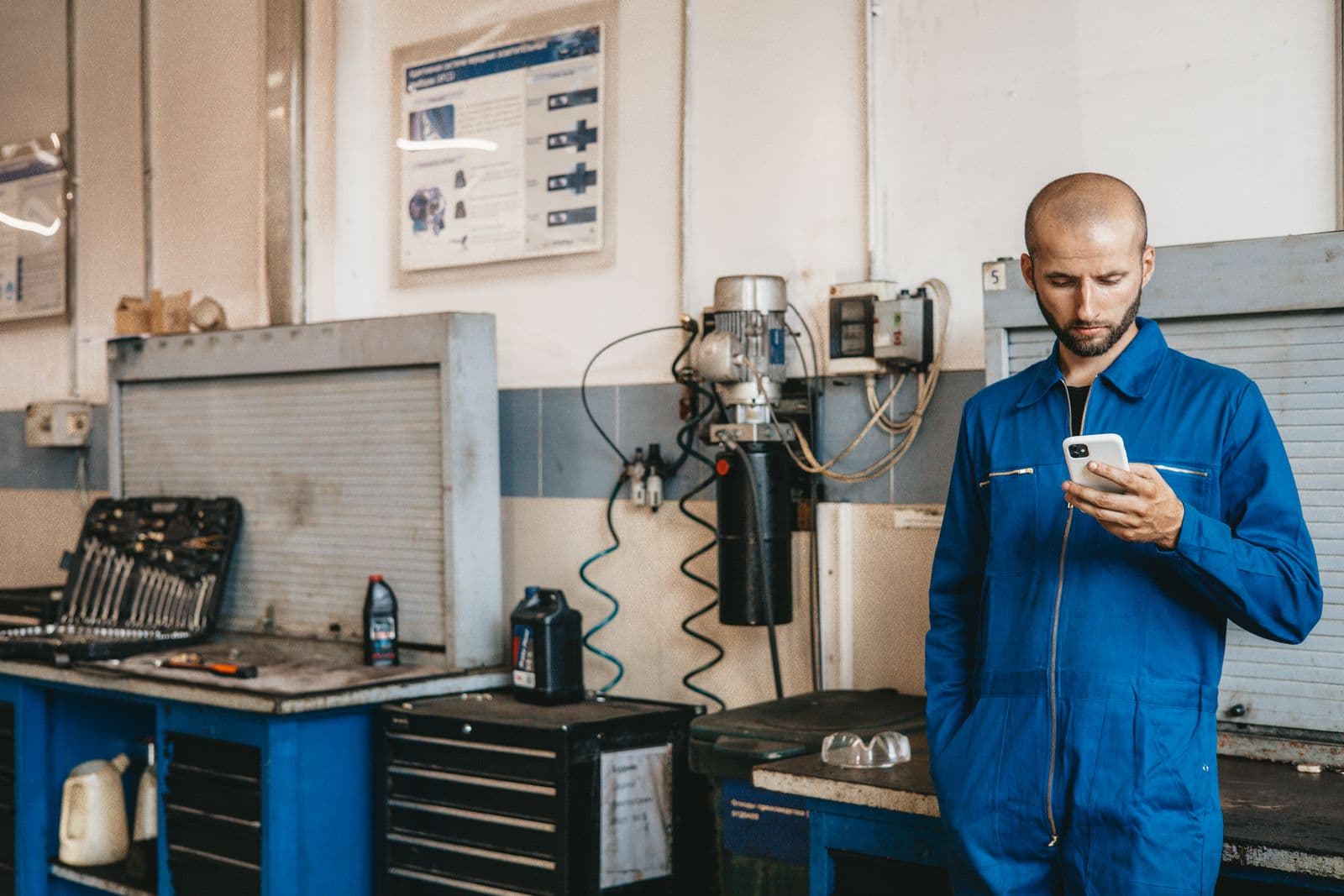 Monteur bekijkt zijn dagplanning op zijn telefoon in de werkplaats